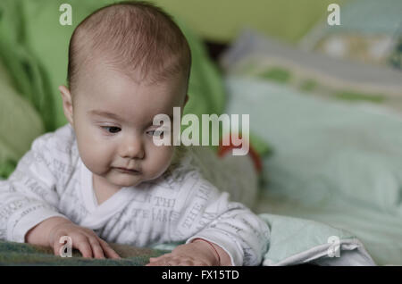 Babymädchen mit blauen Augen lernt zu krabbeln Stockfoto