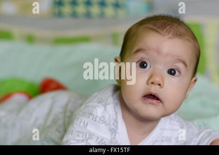 Babymädchen mit blauen Augen lernt zu krabbeln Stockfoto