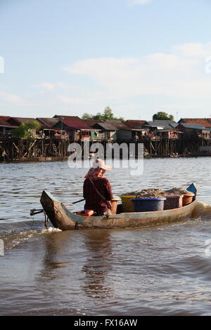 Eine Frau, die Fische mit dem Boot zu den gestelzten Dörfern auf dem Tonle Sap See, Kambodscha Stockfoto