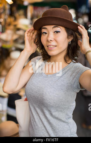 Junge asiatische Frau versucht eine Mütze im Shop. Stockfoto