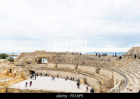 Römische Amphitheater in Tarragona mit Touristen, die das Monument und die Boote im Hintergrund in Tarragona, Katalonien, Spanien Stockfoto