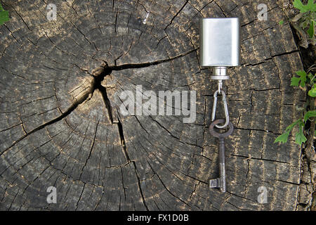 Ein Alter Schlüssel gebunden an ein Fläschchen als ein Schlüsselanhänger, präsentiert auf einem Baumstumpf Stockfoto