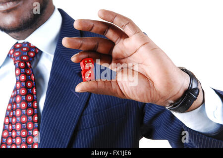 Ein schwarzer Geschäftsmann mit zwei roten Würfel in der Hand, in einem blauen Anzug steht für weißen Hintergrund in Nahaufnahme isoliert. Stockfoto