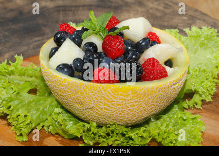 Melonen-Bits, Himbeeren, Brombeeren und Heidelbeeren in einer halbierten und ausgehöhlten Galia-Melone, garniert mit Minze Stockfoto
