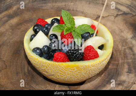 Melonen-Bits, Himbeeren, Brombeeren und Heidelbeeren in einer halbierten und ausgehöhlten Galia-Melone, garniert mit Minze Stockfoto