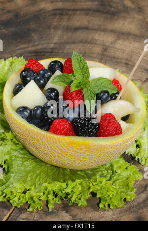Melonen-Bits, Himbeeren, Brombeeren und Heidelbeeren in einer halbierten und ausgehöhlten Galia-Melone, garniert mit Minze Stockfoto