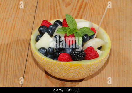Melonen-Bits, Himbeeren, Brombeeren und Heidelbeeren in einer halbierten und ausgehöhlten Galia-Melone, garniert mit Minze Stockfoto