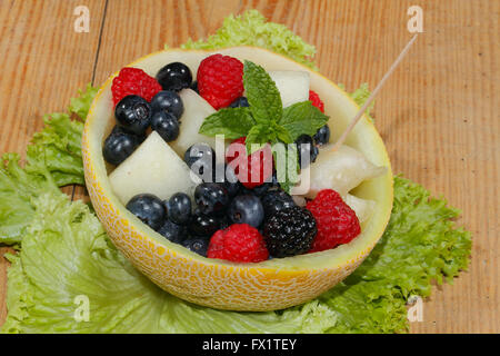 Melonen-Bits, Himbeeren, Brombeeren und Heidelbeeren in einer halbierten und ausgehöhlten Galia-Melone, garniert mit Minze Stockfoto