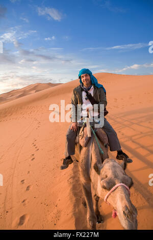 Ein Tourist der Kamelritt und bewundern Sie den Sonnenuntergang von einem Hügel aus. Einige Schleifen Hügel am Erg Chebbi in der Wüste Sahara.  Ers sind groß Stockfoto