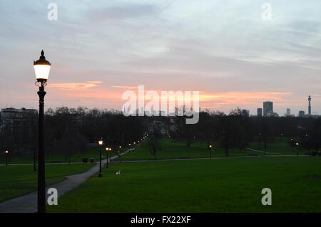 Sonnenaufgang in Primrose Hill mit viktorianischen Lichter und Skyline-Blick mit ikonischen Gebäude BT Tower und weich grau und orange Himmel. Stockfoto