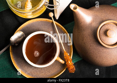 Eine Tasse heißen Tee auf einem Tisch mit Teekanne und Honig. Erschossen von oben Stockfoto