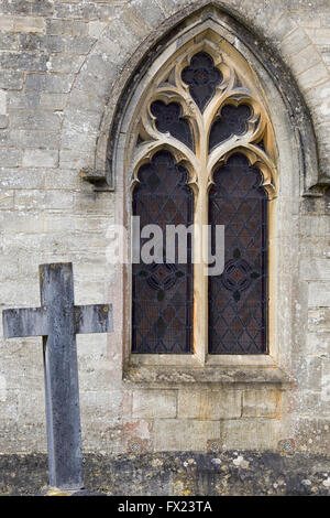 Grabstein neben einem gewölbten Kirchenfenster Stockfoto