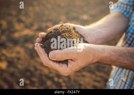 Landwirt Holding Haufen von Ackerboden in Händen, verantwortungsvolle und nachhaltige landwirtschaftliche Produktion hautnah mit selektiven Fokus Stockfoto