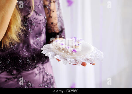 Frau mit einem Kissen mit goldenen Ringen bei Trauung Stockfoto