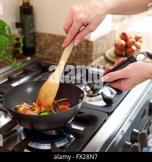 Frau in der Küche unter Rühren braten Gemüse. Stockfoto