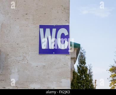 Blaues Schild von öffentlichen Toiletten WC auf einer Steinmauer Stockfoto