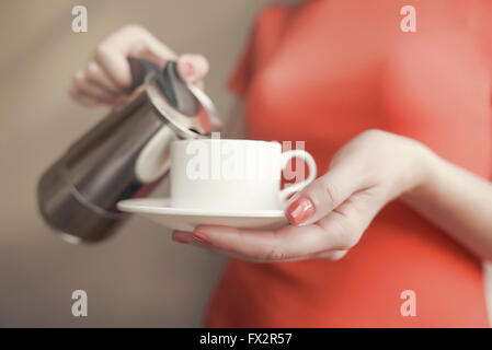 Weibliche Hand gießt Kaffee aus einer Kaffeemaschine ausgestattet. Konzentrieren Sie sich auf die Hand. Stockfoto