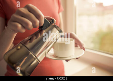 Weibliche Hand gießt Kaffee aus einer Kaffeemaschine ausgestattet. Kaffee im Fokus. Stockfoto