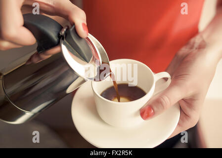 Weibliche Hand gießt Kaffee aus einer Kaffeemaschine ausgestattet. Konzentrieren Sie sich auf die Hand. Stockfoto