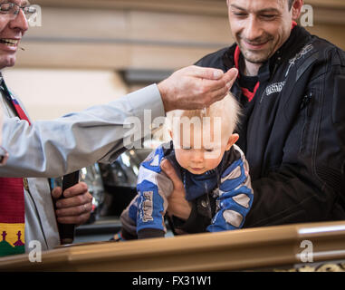 Niedergruendau, Deutschland. 10. April 2016. Pfarrer Thorsten Heinrich (L) tauft kleine Jack, eine Motorrad-Outfit trägt während einem Gottesdienst an der 35. "Anlassen" (lit.) Starten eines Motors) markiert den Beginn der neuen Motorrad-Saison in Niedergruendau, Deutschland, 10. April 2016. Foto: FRANK RUMPENHORST/Dpa/Alamy Live News Stockfoto