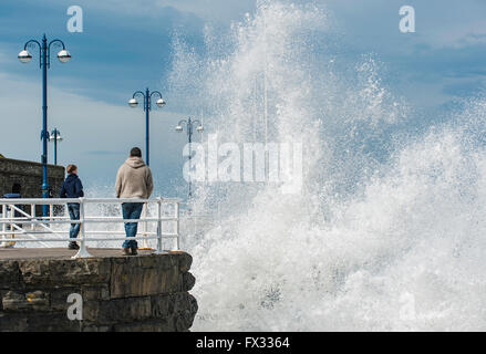 Aberystwyth, Ceredigion, Westwales, 10. April 2016 UK Wetter: zwei Surfer nutzen desto höher als normale Flut an 5,48 m schließen erhöhte Wind und der massiven Wellengang gefährlich surfen entlang der Kai-Mauer als Leute zu beobachten, zu fotografieren und Video genießen noch die windigen Wetter klarem. Bildnachweis: Veteran Fotografie/Alamy Live-Nachrichten Stockfoto