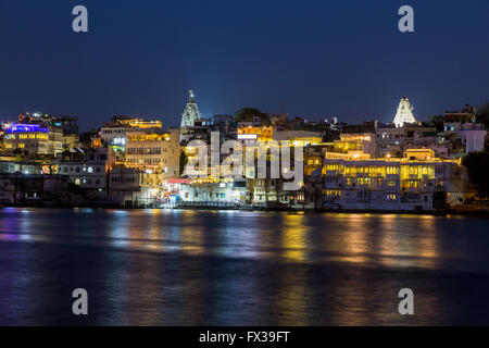 Bestandteil der Udaipur Skyline bei Nacht zeigt viele Bauwerke und Reflexionen im Pichola-See Stockfoto