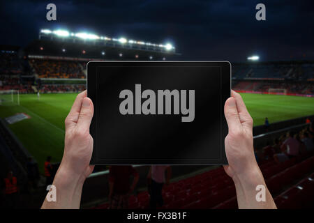 Mann hält Tablet mit leeren Bildschirm auf Fußball-Spiel. Stadion im Hintergrund. Stockfoto