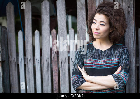 Asiatische Frau steht in der Nähe der Holzzaun. Stockfoto