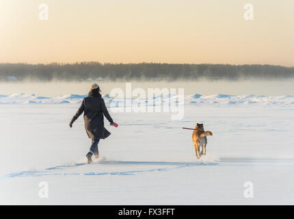 Winter zu Fuß an den ersten sonnigen Tagen auf dem Eis der zugefrorenen Bucht. Stockfoto