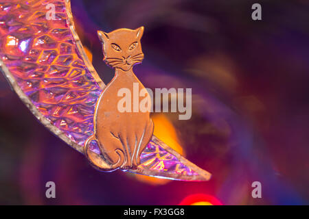 Nahaufnahme von einem Weihnachtsbaum Ornament mit eine Katze sitzt auf einer Mondsichel, beleuchtet von Weihnachtsbaums Stockfoto