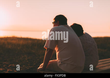 Seitenansicht ein Ehepaar eine Silhouette, die auf einer Bank sitzen. Stockfoto