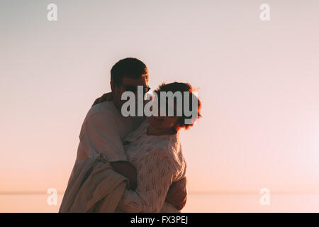 Erwachsenes paar umarmt bei Sonnenuntergang und Meer. Stockfoto