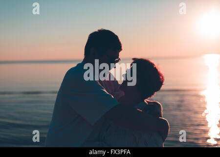 Erwachsenes paar umarmt bei Sonnenuntergang und Meer. Stockfoto