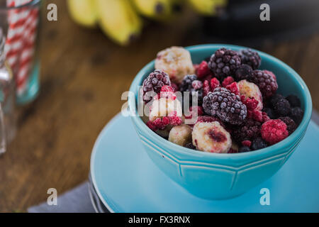 Gefrorene Beeren, Smoothie Zutaten. In pulsierende blaue Schüssel auf Holztisch Stockfoto