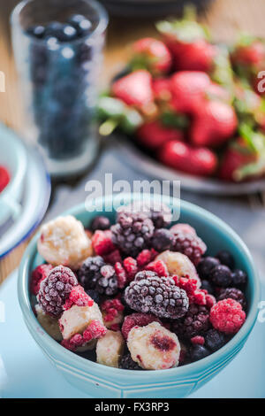 Gefrorene Beeren, Smoothie Zutaten. In pulsierende blaue Schüssel auf Holztisch Stockfoto