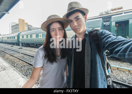 Asiatische junge Paare, die Spaß im Bahnhof nehmen selfie Stockfoto