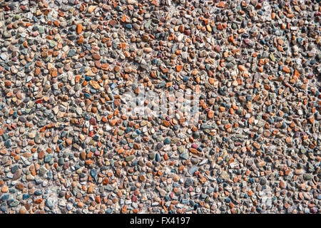 Zerkleinerte Kies in Betonmauer verputzt Textur. Stockfoto