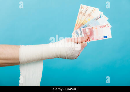 Korruption im Gesundheitswesen. Teil Körper männliche bandagierte Hand mit Geld und lange weiße Bandage auf blau. Stockfoto