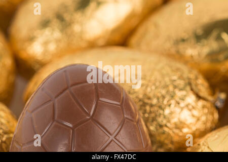 über Nachsicht in Schokolade Ostereier eingewickelt in glänzender Goldfolie in Reihen bereit für Schokoholiker Übergewicht Gesundheitsproblem Stockfoto