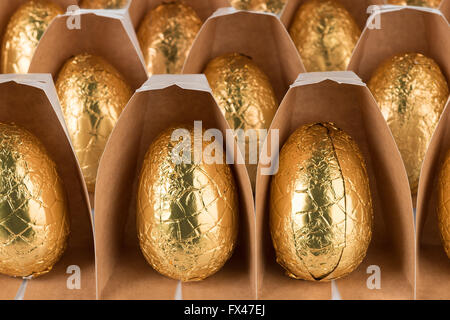 über Nachsicht in Schokolade Ostereier eingewickelt in glänzender Goldfolie in Reihen bereit für Schokoholiker Übergewicht Gesundheitsproblem Stockfoto