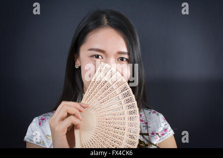 Schöne asiatische Frau hält einen Handventilator Stockfoto