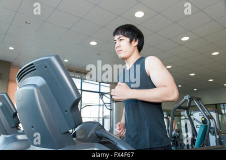 Asiatische junge Mann läuft auf Laufband im Fitness-Studio Stockfoto