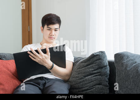 Asiatische junge Mann denken und Fragen sich, während des Schreibens einer Papiers zu Hause Stockfoto