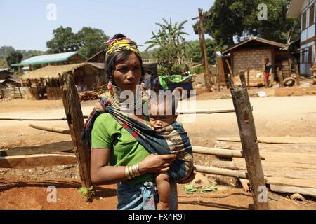 Demoso, Myanmar. 11. April 2016. Eine Padaung-Frau mit Messingringe um den Hals trägt ihr Kind in Panpet Dorf, Demoso Township, Kayah-Staat, Myanmar, 11. April 2016. Die Messingringe werden zuerst angewendet, wenn die Padaung-Mädchen ungefähr acht Jahre alt sind und als das Mädchen älter, längere Spulen, um 24 oder 25 Ringe addiert werden. © U Aung/Xinhua/Alamy Live-Nachrichten Stockfoto