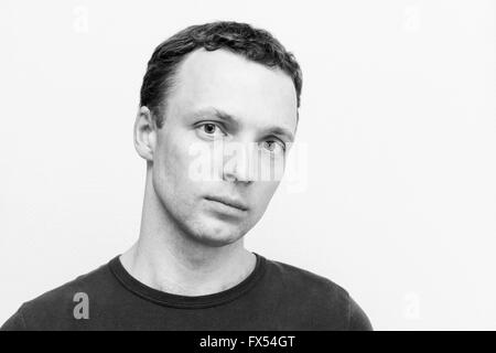 Ernsthafte kaukasischen Jüngling, close-up Studioportrait über weiße Wand Hintergrund, schwarz / weiß Foto Stockfoto
