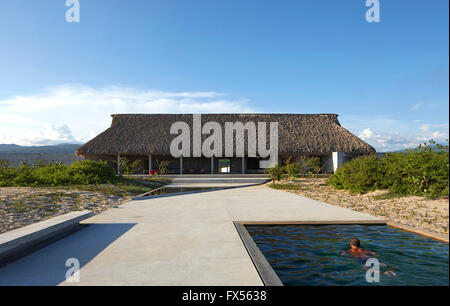 Ozean-Seitenansicht zur wichtigsten Palapa mit Künstler im Pool. Casa Wabi, Puerto Escondido, Mexiko. Architekt: Tadao Ando, 2015. Stockfoto