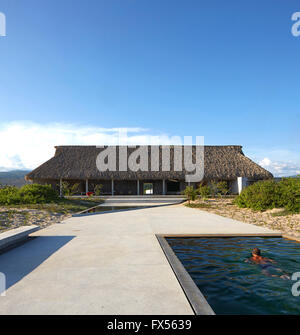 Ozean-Seitenansicht zur wichtigsten Palapa mit Künstler im Pool. Casa Wabi, Puerto Escondido, Mexiko. Architekt: Tadao Ando, 2015. Stockfoto