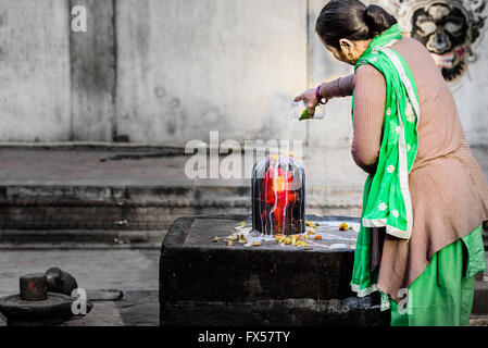 Ein weiblicher Anhänger Shiva Lingam in einem hinduistischen Tempel in Nepal in Milch gießen Stockfoto