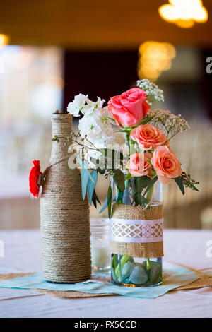 DIY Hochzeit Dekoration Tischdekoration mit Weinflaschen in Sackleinen Schnur gewickelt und rose Blumen. Stockfoto