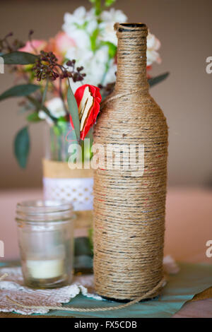 DIY Hochzeit Dekoration Tischdekoration mit Weinflaschen in Sackleinen Schnur gewickelt und rose Blumen. Stockfoto